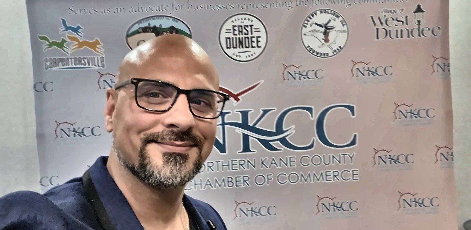 Eric Mina in front of the Northern Kane County Chamber of Commerce backdrop